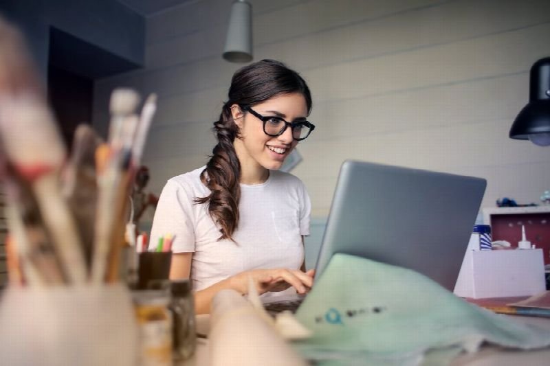 Smiling woman working on a laptop at a creative desk