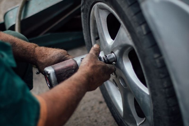 Mechanic using an impact wrench on a car wheel