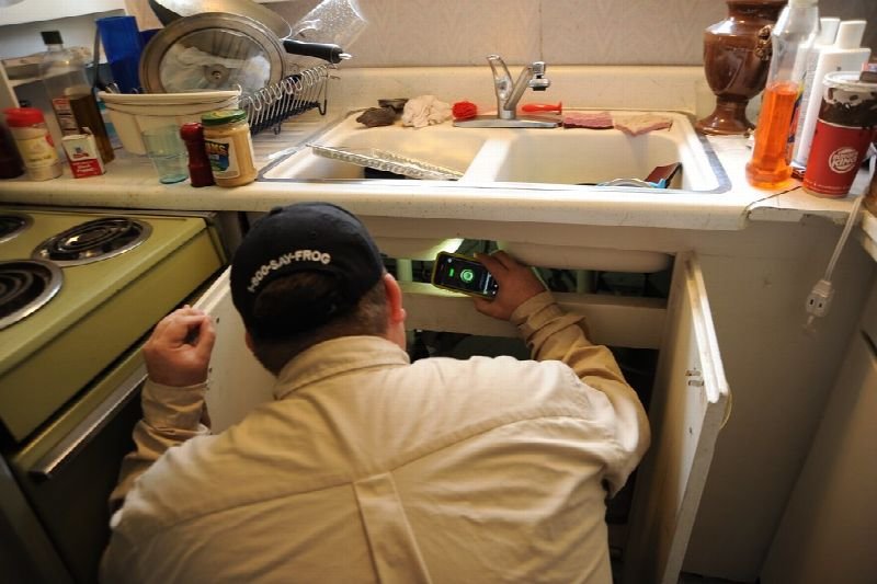 Technician inspecting the cabinet under a kitchen sink