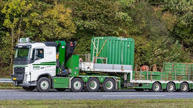 Green semi truck hauling a flatbed trailer on a highway