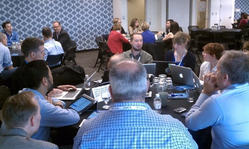 Group of people meeting around tables in a conference room