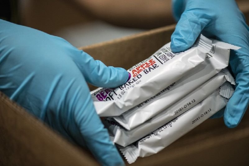 Gloved hands packing products into a cardboard shipping box