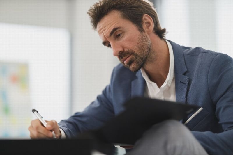 Professional reviewing paperwork on a clipboard at an office desk